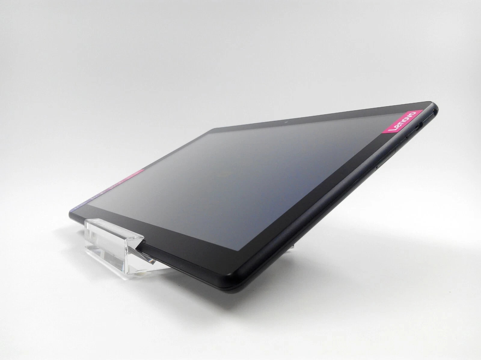 A black Lenovo tablet resting on a clear acrylic stand against a light gray studio background.